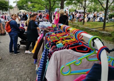 Kleiderständer mit Kleidung und Marktgeschehen beim Karower Familien-Flohmarkt in Berlin-Karow