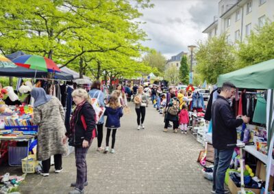Marktgang mit Ständen, Besuchern und grüner Allee beim Karower Familien-Flohmarkt in Berlin-Karow